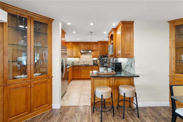 a kitchen with stainless steel appliances granite countertop a table chairs and a refrigerator