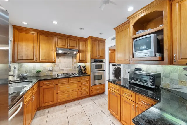 a kitchen with stainless steel appliances granite countertop wooden cabinets a stove top oven a sink and dishwasher