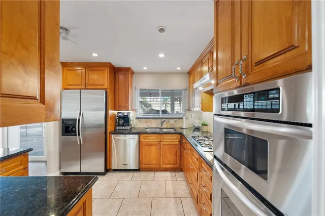 a kitchen with stainless steel appliances granite countertop a refrigerator a stove and a sink