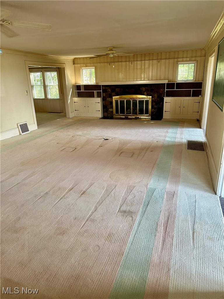 5452 Woodside Road Mentor, OH 44060 - Photo 10 of 19 Unfurnished living room with light carpet, a ceiling fan, crown molding, a fireplace, and plenty of natural light