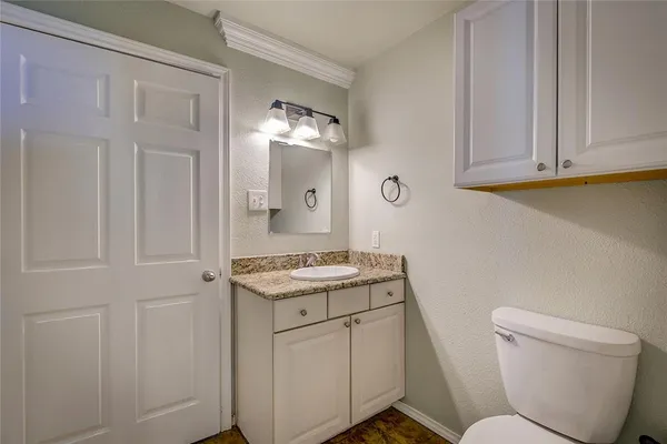 a bathroom with a granite countertop toilet sink and mirror