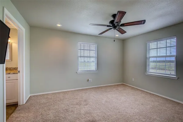 an empty room with windows and fan