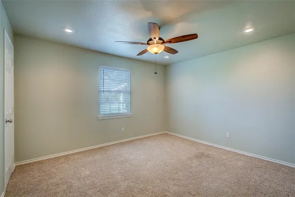 an empty room with a ceiling fan and window
