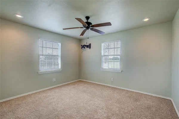 en empty room with windows and ceiling fan