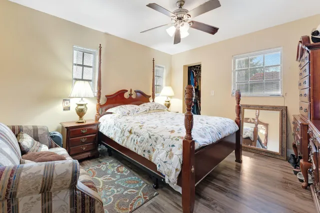 a bedroom with a bed a dresser and wooden floor