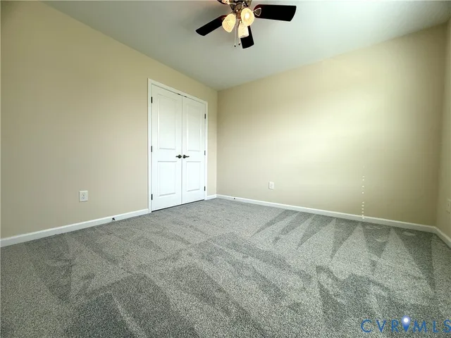an empty room with a ceiling fan and carpet