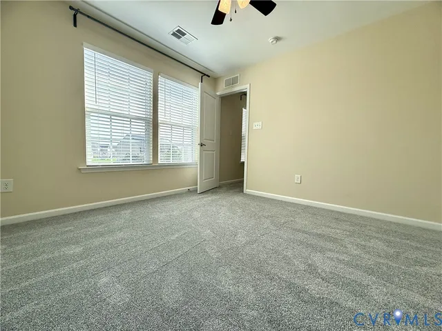 an empty room with ceiling fan and window