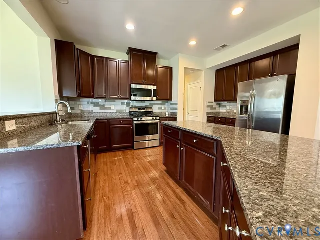 a large kitchen with stainless steel appliances granite countertop a stove refrigerator and a sink