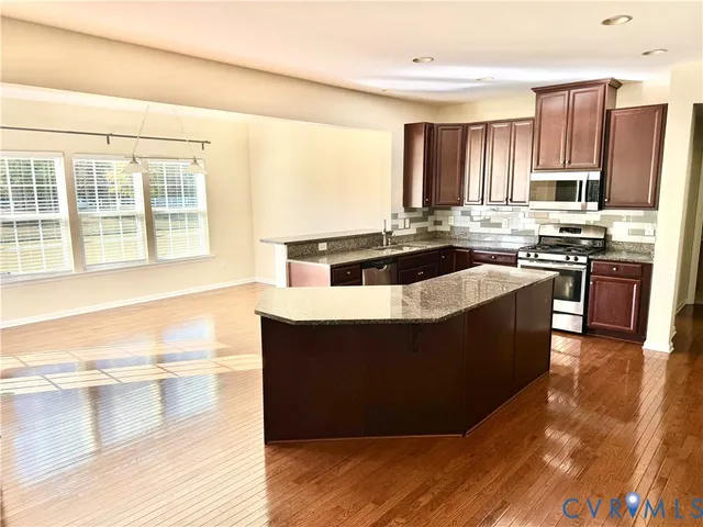 a kitchen with stainless steel appliances granite countertop a stove a sink and a refrigerator