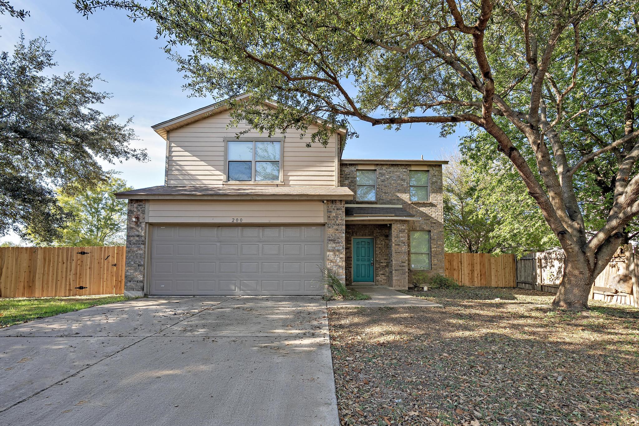 200 Lexington Kyle, TX 78640 - Photo 2 of 25 Traditional-style home with an attached garage, concrete driveway, and brick siding