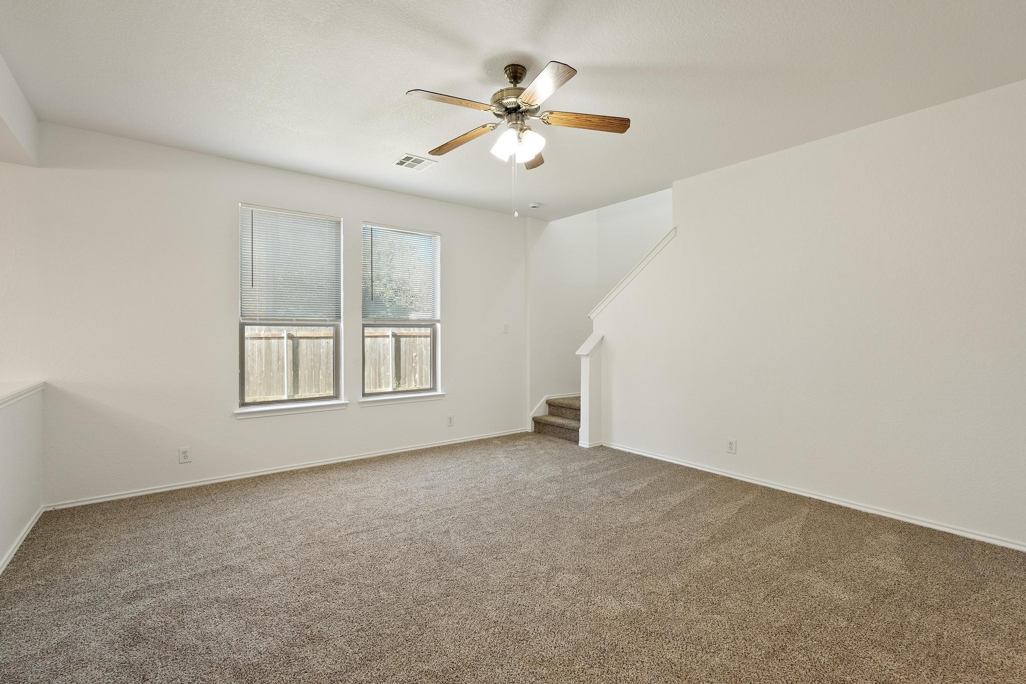 200 Lexington Kyle, TX 78640 - Photo 4 of 25 Unfurnished living room featuring stairway, carpet flooring, and a ceiling fan