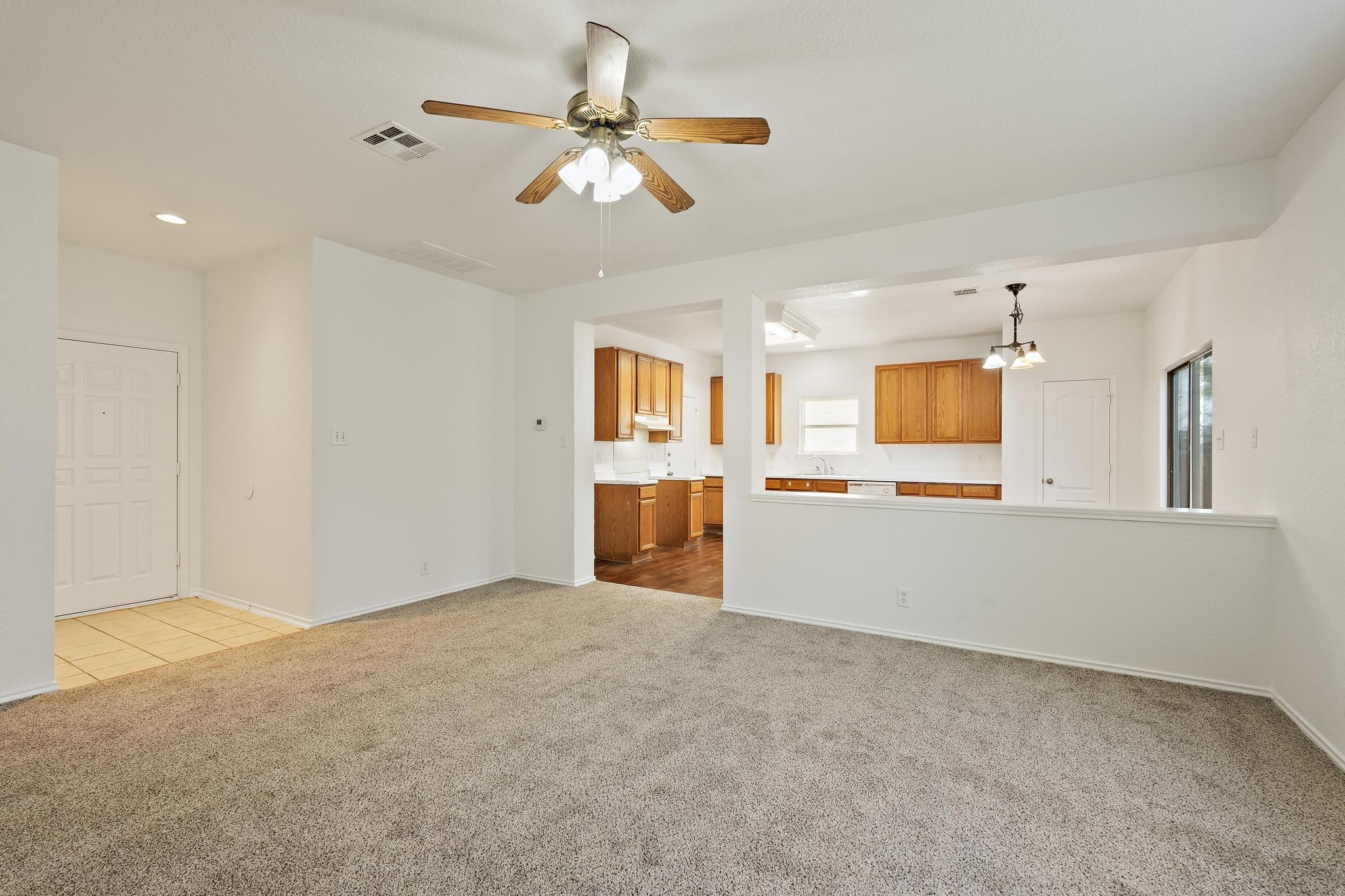 200 Lexington Kyle, TX 78640 - Photo 6 of 25 Unfurnished living room with light carpet, a ceiling fan, and a chandelier