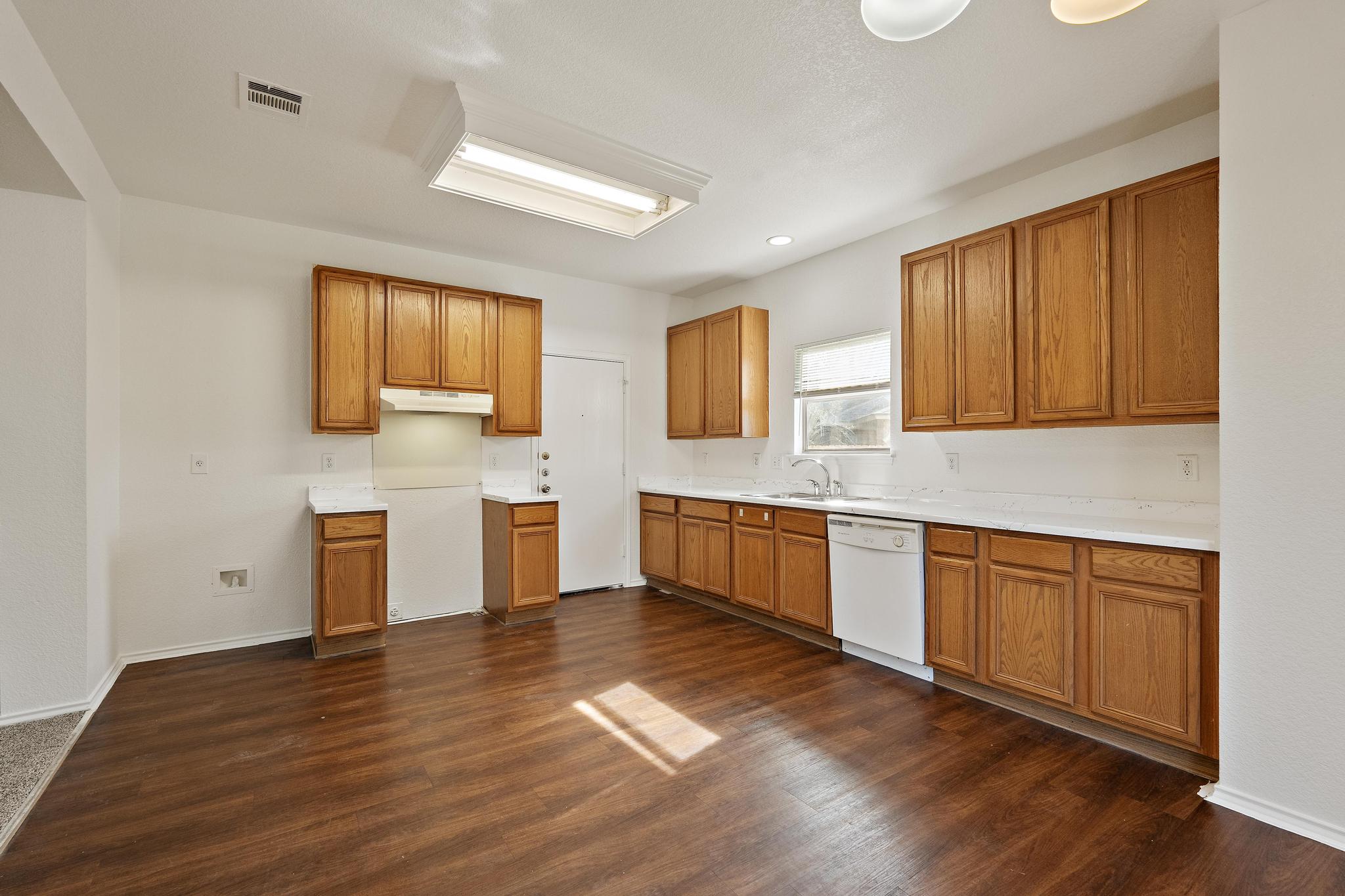 200 Lexington Kyle, TX 78640 - Photo 8 of 25 Kitchen featuring brown cabinetry, light countertops, dishwasher, dark wood-style floors, and under cabinet range hood