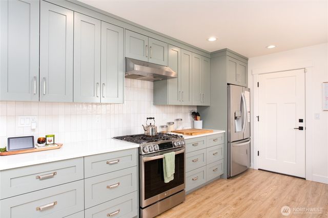a kitchen with stainless steel appliances white cabinets and a refrigerator