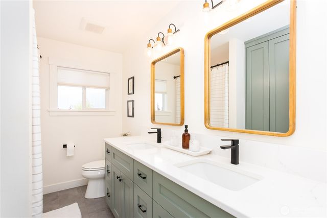 a bathroom with a double vanity sink mirror and toilet