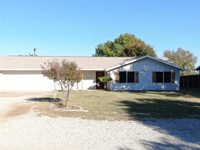 a view of a yard in front of a house with a large tree