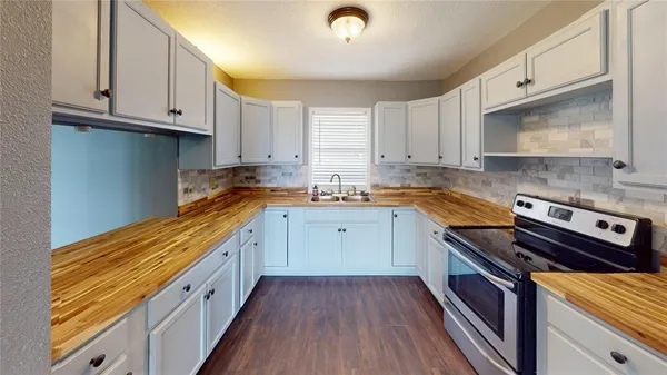 a kitchen with granite countertop a stove a sink and dishwasher wooden cabinets with granite countertops