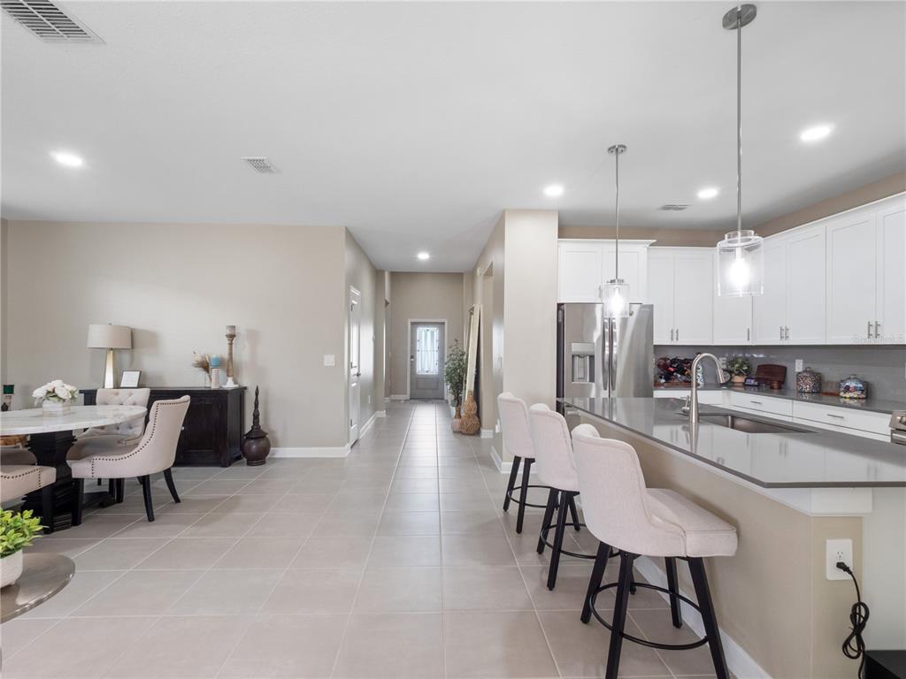 4531 Hillingdam Road Davenport, FL 33837 - Photo 11 of 36 a room with stainless steel appliances kitchen island granite countertop a dining table chairs and a refrigerator