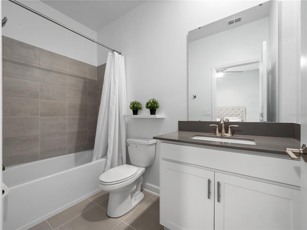 4531 Hillingdam Road Davenport, FL 33837 - Photo 22 of 36 a bathroom with a granite countertop sink toilet a large mirror a bathtub and shower