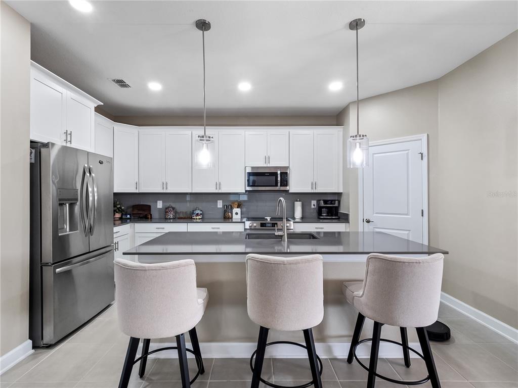 4531 Hillingdam Road Davenport, FL 33837 - Photo 9 of 36 a kitchen with stainless steel appliances granite countertop a sink a stove a refrigerator and island with wooden floor