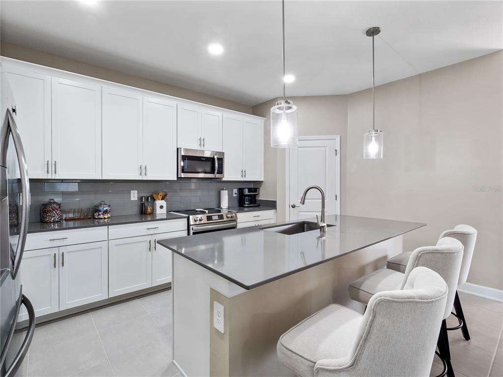 4531 Hillingdam Road Davenport, FL 33837 - Photo 10 of 36 a kitchen with a sink white cabinets and stainless steel appliances