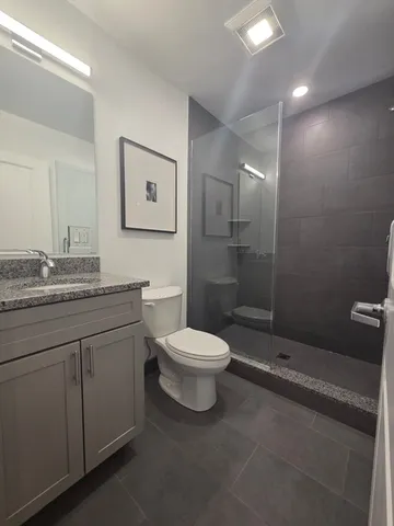 a bathroom with a granite countertop toilet a sink and mirror