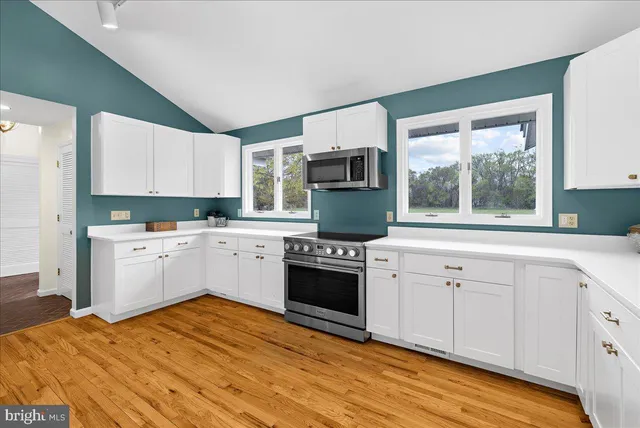a kitchen with stainless steel appliances granite countertop a stove a sink and white cabinets