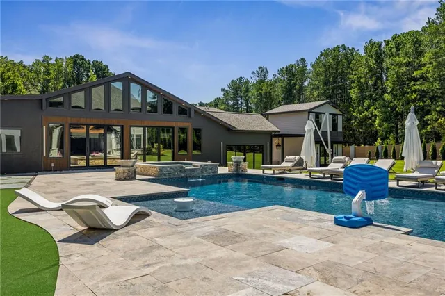a view of a house with pool fire pit and chairs in patio