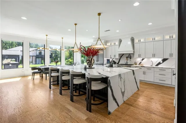 a kitchen with stainless steel appliances kitchen island granite countertop a table chairs and a view of living room