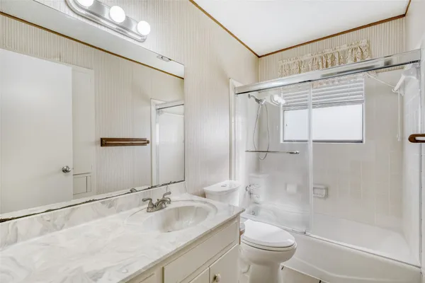 a bathroom with a granite countertop sink a toilet and shower