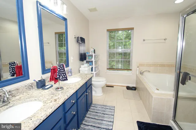 a bathroom with a granite countertop sink mirror vanity bathtub and a shower