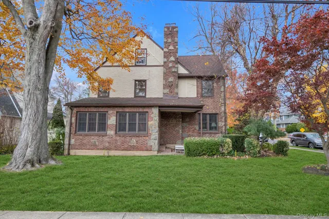 a view of a house with brick walls and a yard with a large tree