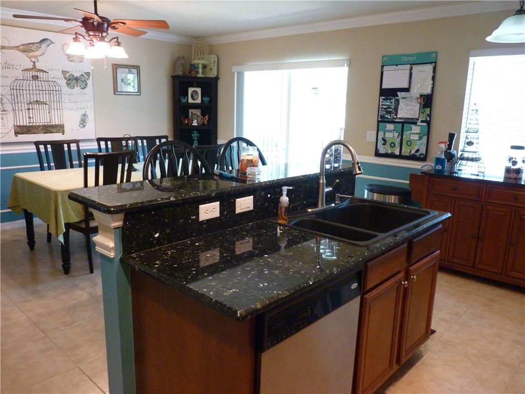 5298 Southeast Mitchell Lane Stuart, FL 34997 - Photo 8 of 33 a kitchen with granite countertop a table chairs stove and cabinets