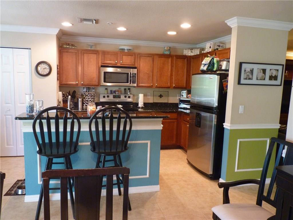 5298 Southeast Mitchell Lane Stuart, FL 34997 - Photo 9 of 33 a kitchen with stainless steel appliances granite countertop a refrigerator a stove a sink a dining table and chairs with wooden floor