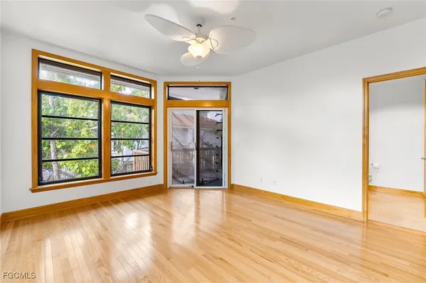a view of an empty room with a window and wooden floor
