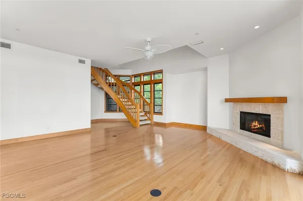 a view of an empty room with wooden floor fireplace and a window