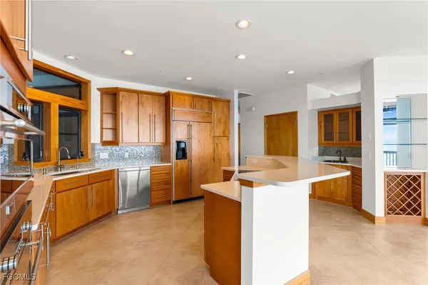 a large white kitchen with stainless steel appliances granite countertop a stove and a sink