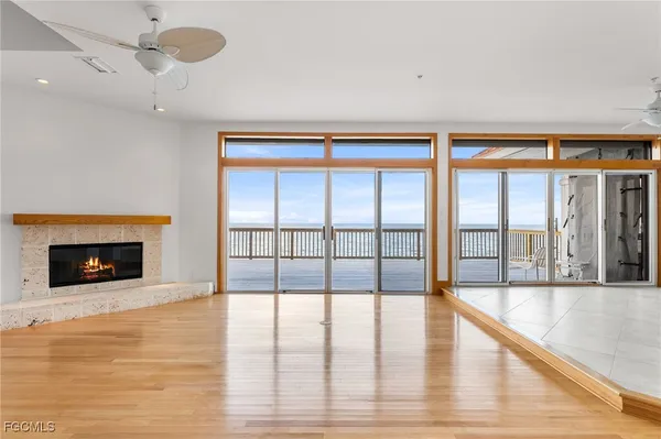 a view of an empty room with wooden floor and a fireplace