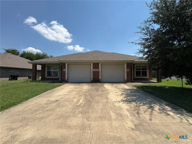 a front view of a house with a garden and trees
