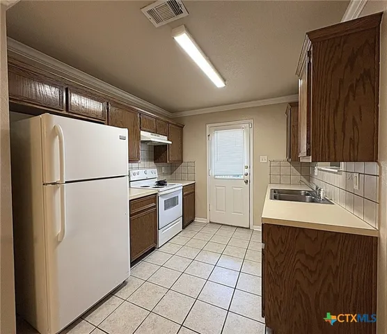 a kitchen with a sink a refrigerator and cabinets