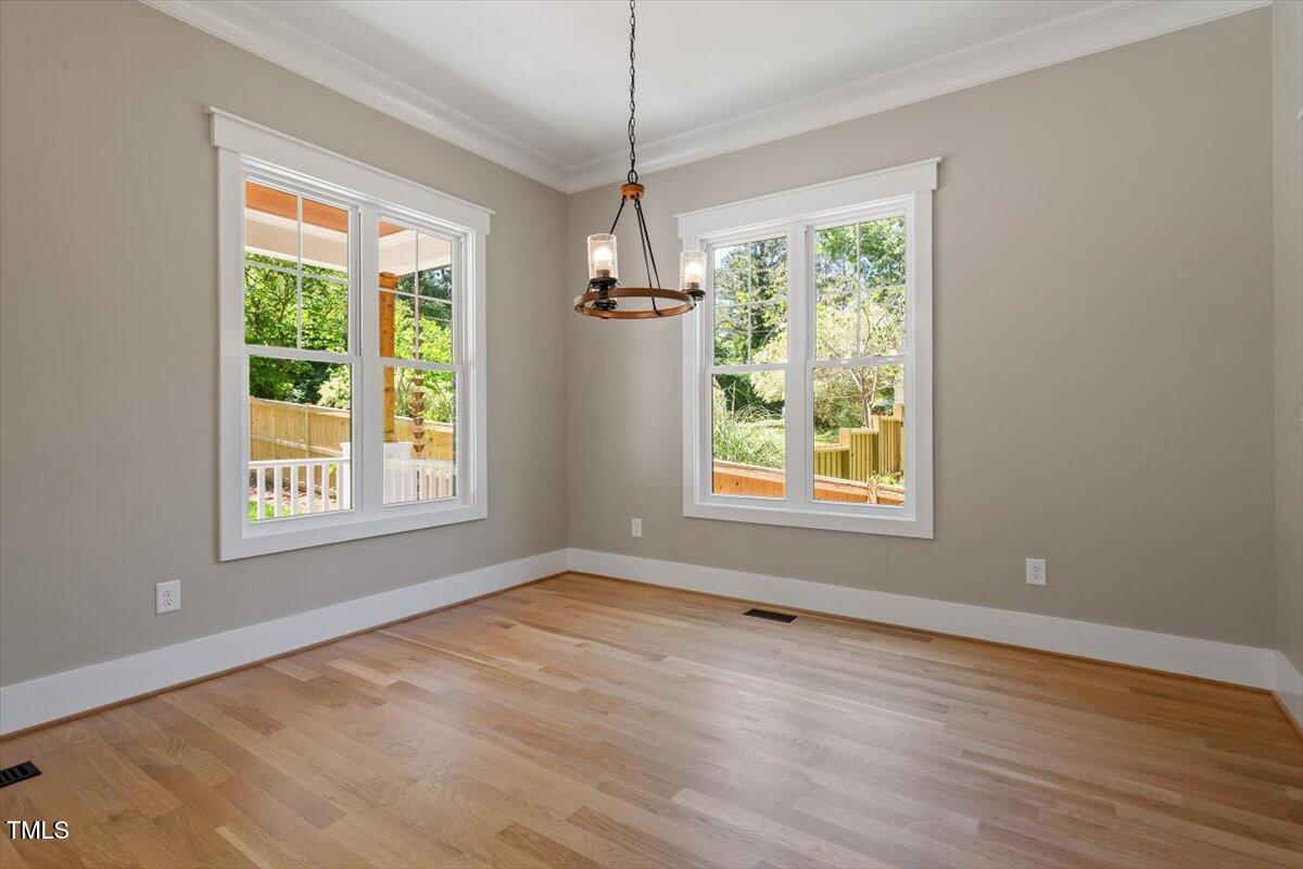 3934 Old Chapel Hill Road Durham, NC 27707 - Photo 15 of 47 a view of an empty room with wooden floor windows and a chandelier