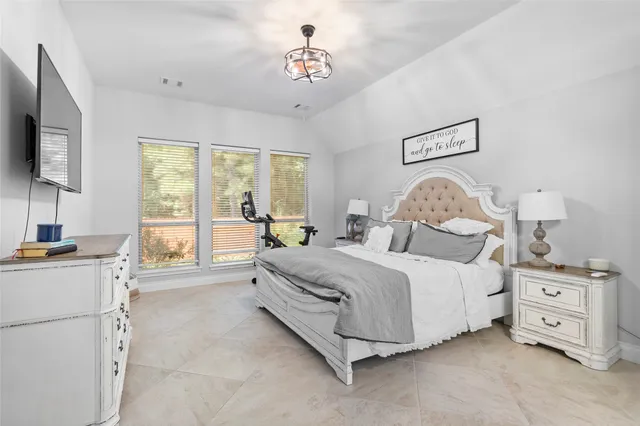 a large bedroom with a bed and a flat tv screen on dresser