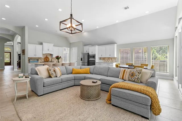 a living room with furniture kitchen view and a chandelier