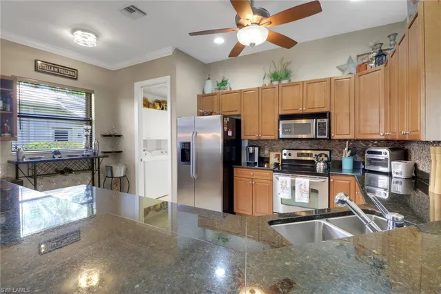 a kitchen with stainless steel appliances granite countertop a refrigerator a stove top oven a sink and dishwasher