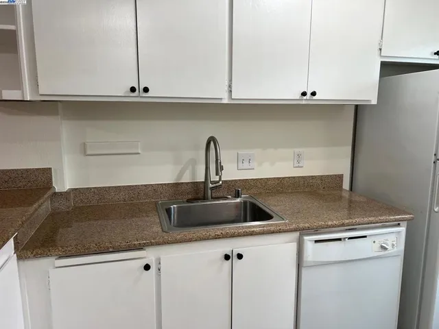 a kitchen with granite countertop white cabinets and a sink
