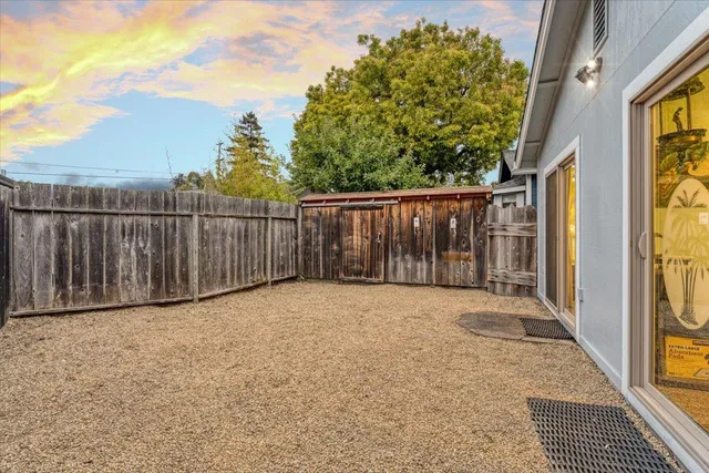 a view of backyard with wooden fence and trees