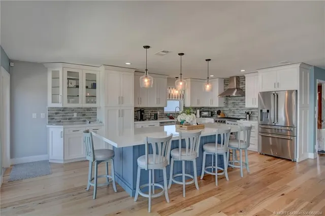 a kitchen with stainless steel appliances kitchen island granite countertop a dining table chairs stove and white cabinets