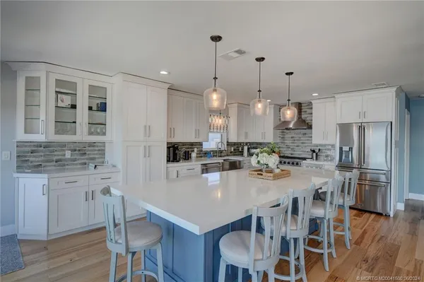 a large kitchen with kitchen island a dining table chairs and a refrigerator