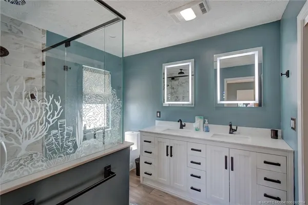 a bathroom with a granite countertop sink a mirror and shower