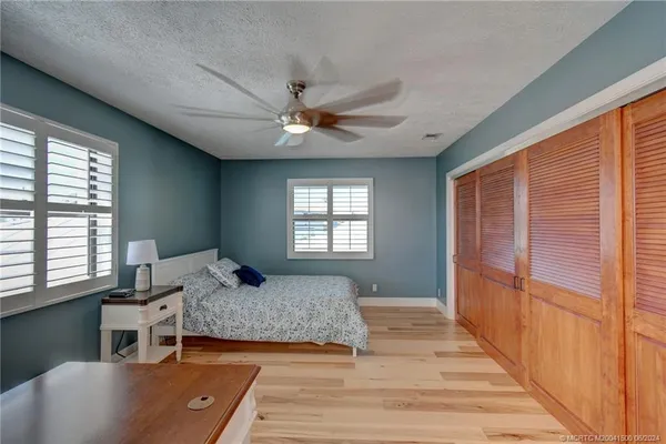 a dining room with wooden floor a chandelier fan a wooden table and chairs
